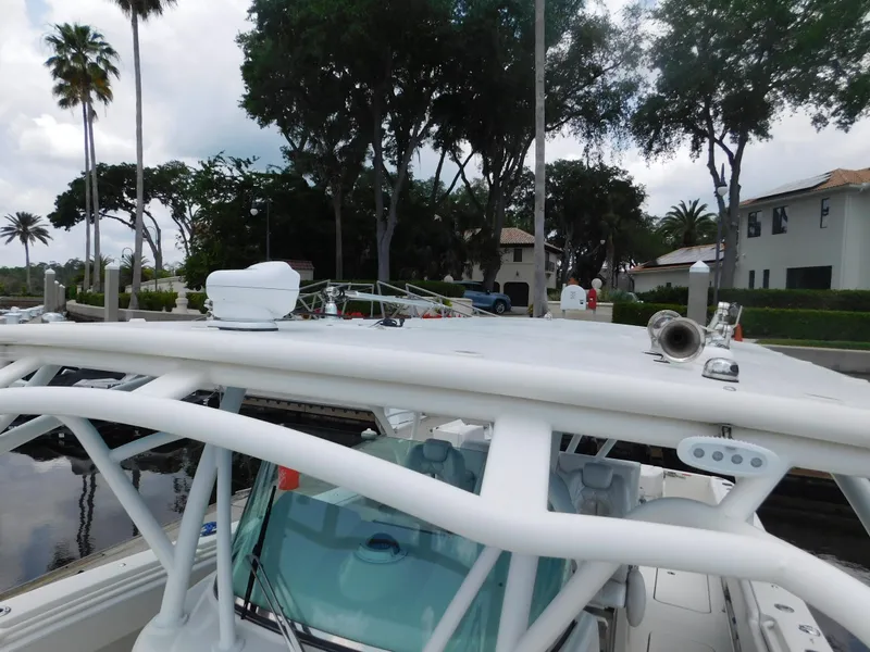 Slide: The Image of 2013 Hydra-Sports 4200 Siesta boat docked, featuring a sturdy white roof and lush surroundings. - 19