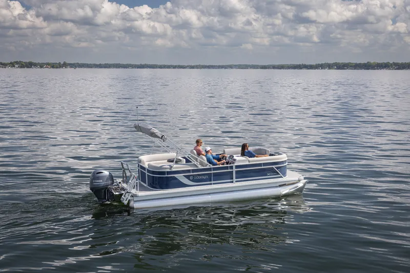 Slide: The Image of 2025 Godfrey EX2086SBX pontoon boat cruising on a calm lake under a cloudy sky. - 22