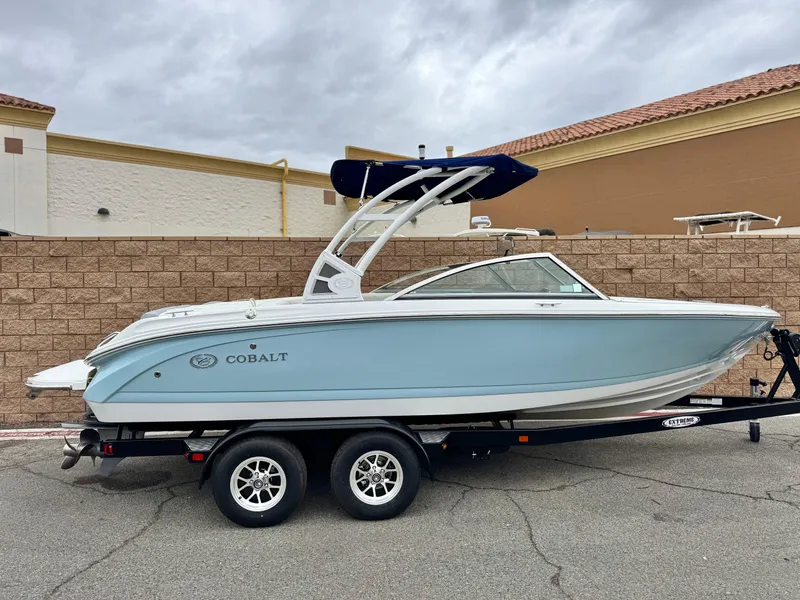 Slide: The Image of 2020 Cobalt 220S boat on trailer, light blue hull, parked outdoors. - 0