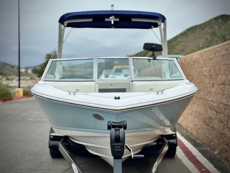 Slide: The Image of 2020 Cobalt 220S boat on trailer, parked outdoors with hills in the background. - 2