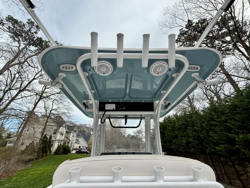 Slide: The Image of 2019 Sea Hunt Gamefish 25 boat with T-top and rod holders, surrounded by trees. - 12