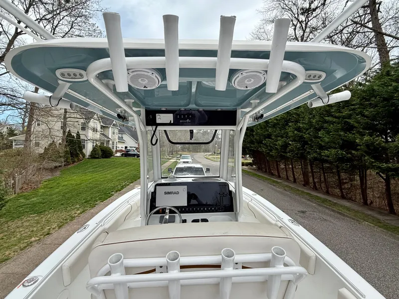Slide: The Image of 2019 Sea Hunt Gamefish 25 boat with rod holders and console, parked on a residential street. - 20