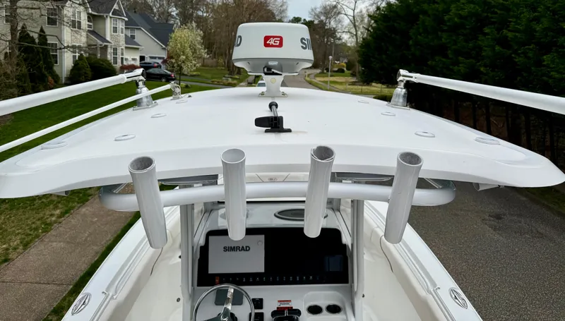 Slide: The Image of 2019 Sea Hunt Gamefish 25 boat with radar and rod holders, parked in a residential area. - 4