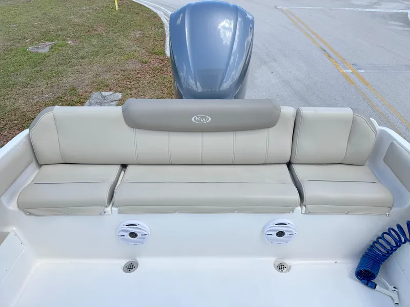 Slide: The Image of 2023 Key West 239 FS boat with cushioned seating and motor, parked on a road. - 22