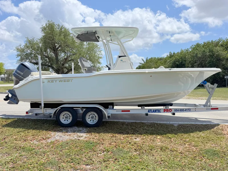 Slide: The Image of 2023 Key West 239 FS boat on trailer, parked outdoors under a partly cloudy sky. - 5
