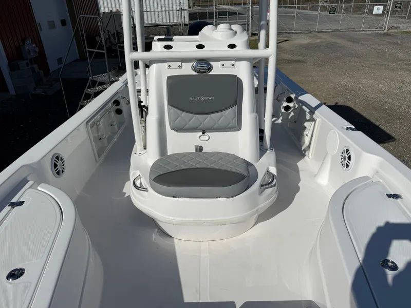Slide: The Image of 2025 NauticStar 214 Shallow Bay boat interior with seating and console, in a marina setting. - 12