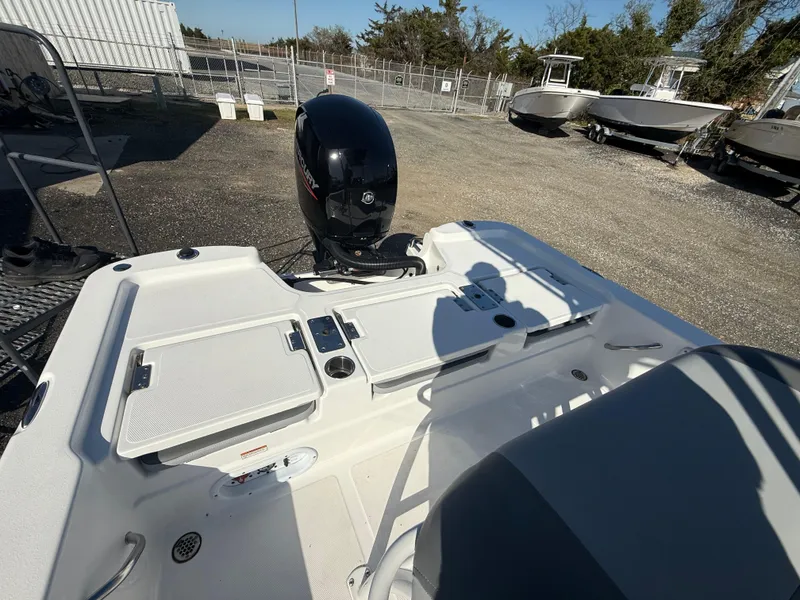 Slide: The Image of 2025 NauticStar 214 Shallow Bay boat with outboard motor, parked outdoors. - 15