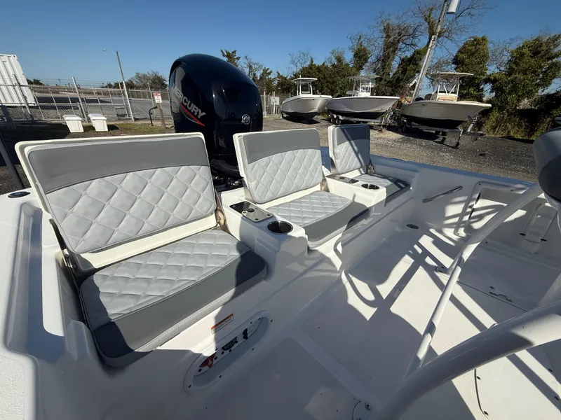 Slide: The Image of 2025 NauticStar 214 Shallow Bay boat interior with cushioned seating and Mercury engine. - 16