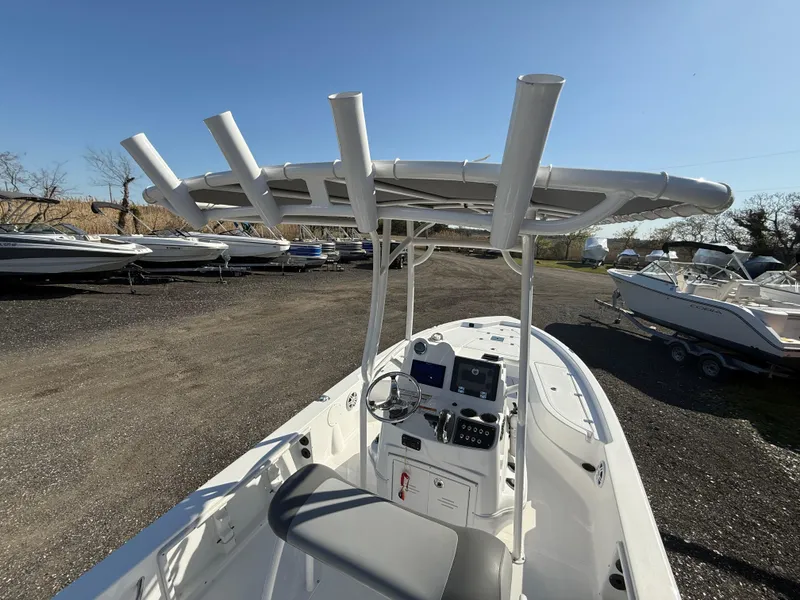 Slide: The Image of 2025 NauticStar 214 Shallow Bay boat with T-top and console, parked on gravel lot. - 18