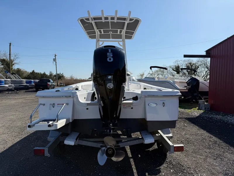 Slide: The Image of 2025 NauticStar 214 Shallow Bay boat with outboard motor, parked outdoors. - 4