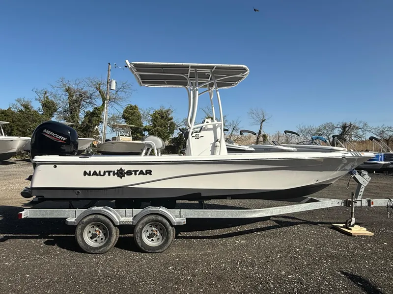 Slide: The Image of 2025 NauticStar 214 Shallow Bay boat on trailer, side view, clear sky background. - 6