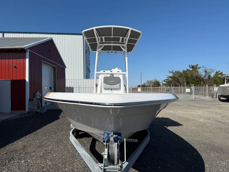 Slide: The Image of 2025 NauticStar 214 Shallow Bay boat on trailer, parked outside a red and white building. - 8