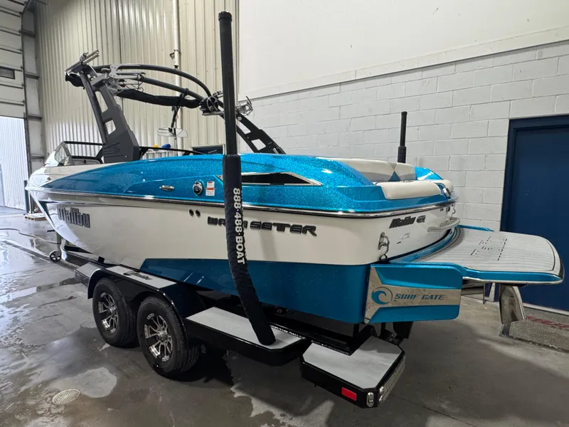 Slide: The Image of 2017 Malibu Wakesetter 23 LSV boat in a garage, blue and white exterior. - 2