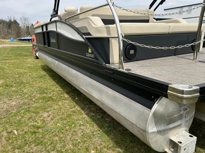 Slide: The Image of 2021 Barletta C24UC Triple Toon pontoon boat on grass, showcasing sleek design and seating. - 11