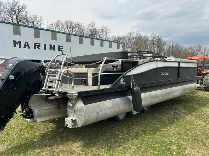 Slide: The Image of 2021 Barletta C24UC Triple Toon pontoon boat parked on grass near a marine building. - 29