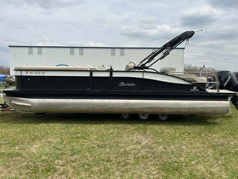 Slide: The Image of 2021 Barletta C24UC Triple Toon pontoon boat on grass, side view. - 3
