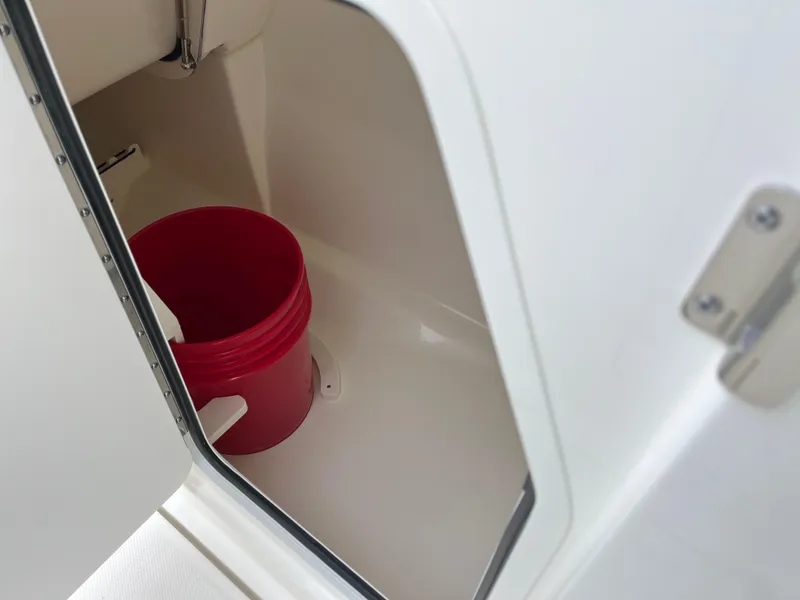 Slide: The Image of Open storage compartment on 2025 Boston Whaler 240 Vantage with red bucket inside. - 15