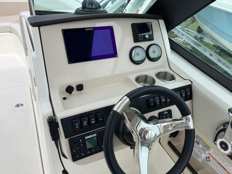 Slide: The Image of 2025 Boston Whaler 240 Vantage dashboard with steering wheel, gauges, and navigation screen. - 2