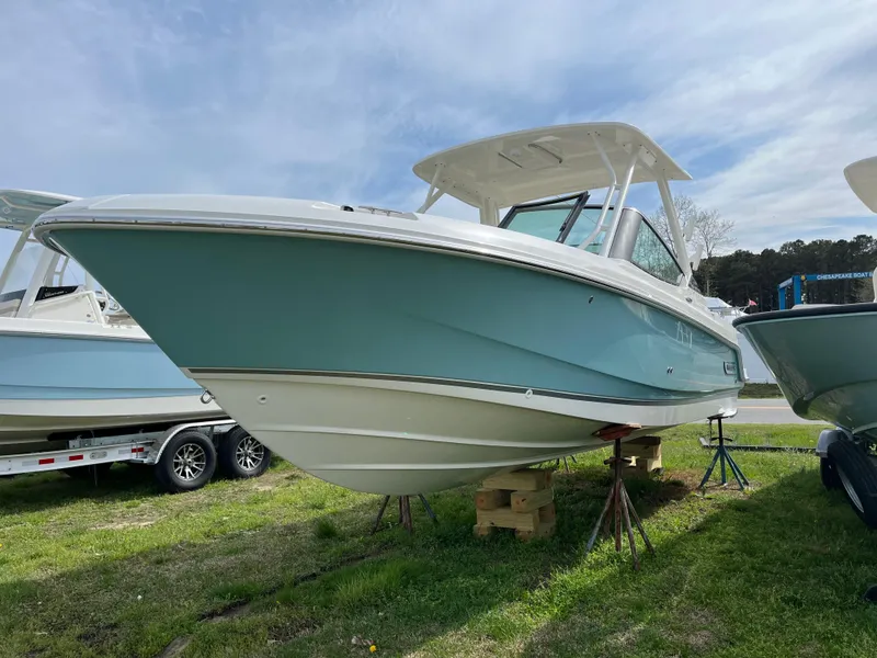 Slide: The Image of 2025 Boston Whaler 240 Vantage boat on display, light blue hull, parked on grass. - 34