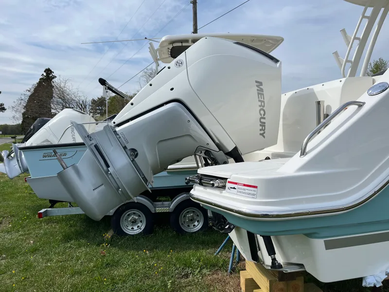 Slide: The Image of 2025 Boston Whaler 240 Vantage with Mercury outboard engines on a trailer, parked on grass. - 37