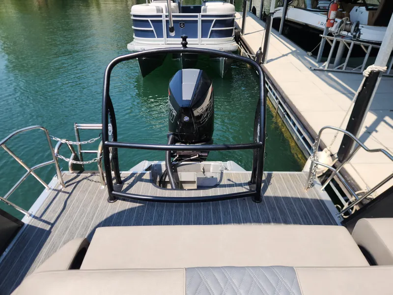 Slide: The Image of 2023 Premier 250 Intrigue RL pontoon boat with outboard motor, docked on calm water. - 14