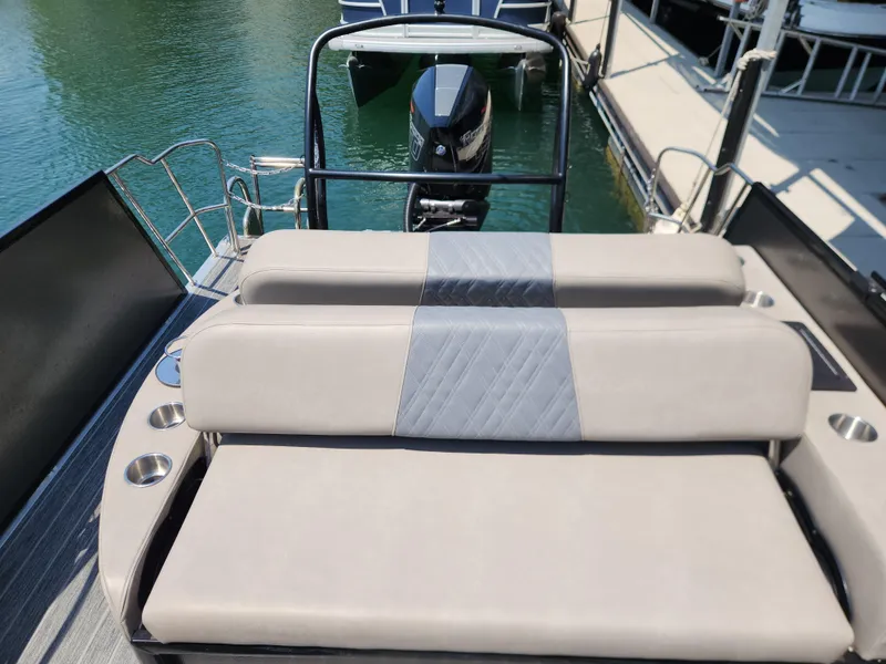 Slide: The Image of 2023 Premier 250 Intrigue RL boat with cushioned seating and outboard motor at dock. - 16