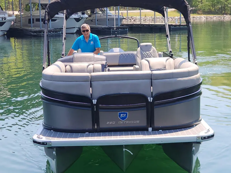 Slide: The Image of 2023 Premier 250 Intrigue RL pontoon boat on water, featuring spacious seating and canopy. - 2