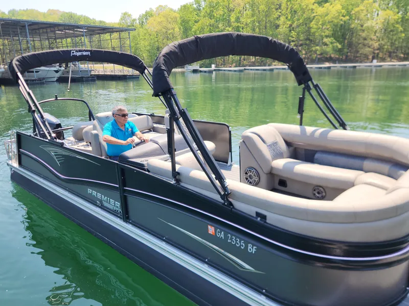 Slide: The Image of 2023 Premier 250 Intrigue RL pontoon boat on a serene lake with lush greenery. - 6