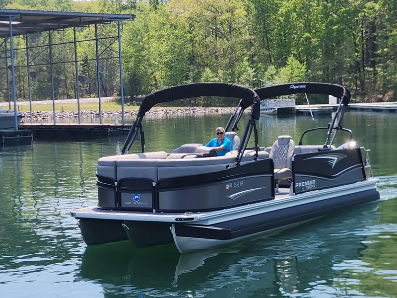 Slide: The Image of 2023 Premier 250 Intrigue RL pontoon boat cruising on a serene lake. - 7