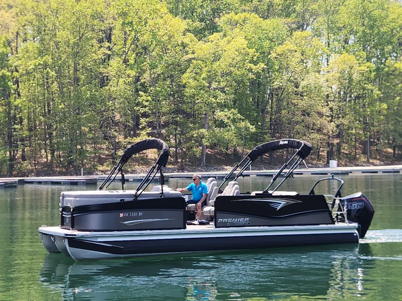 Slide: The Image of 2023 Premier 250 Intrigue RL pontoon boat on a serene lake with lush green trees. - 8