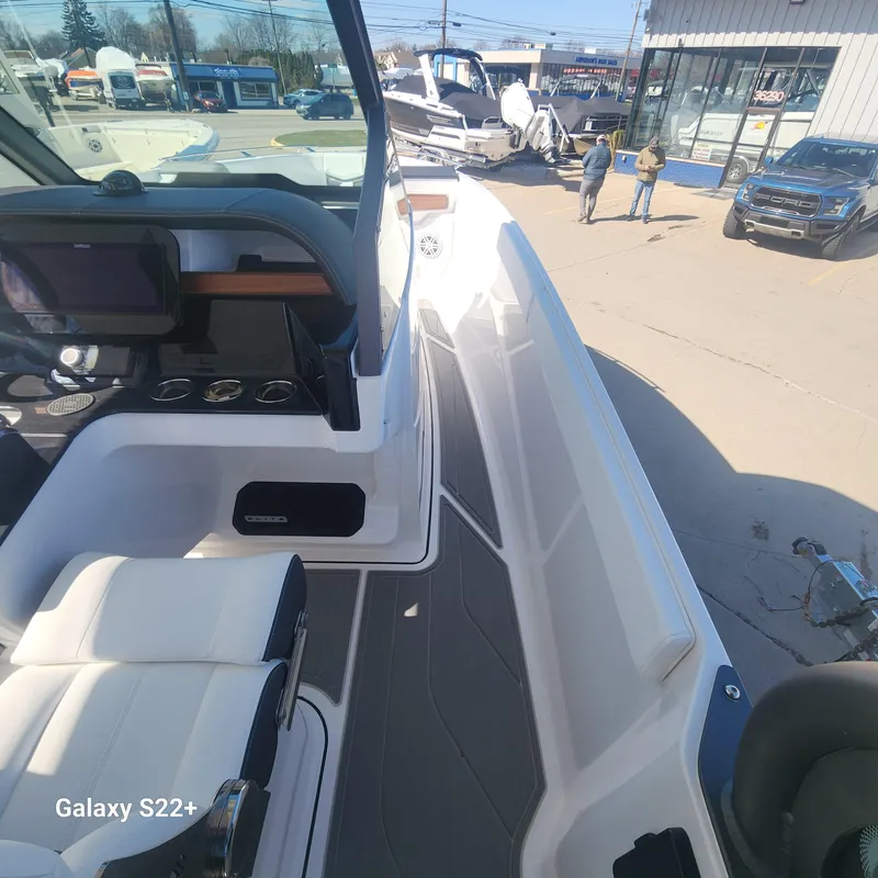 Slide: The Image of 2025 Monterey Elite 27 OB boat interior with seating and dashboard, parked outdoors. - 6