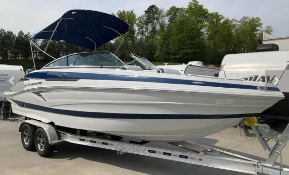 Slide: The Image of 2023 Crownline 260 XSS boat on trailer with canopy, parked outdoors. - 0