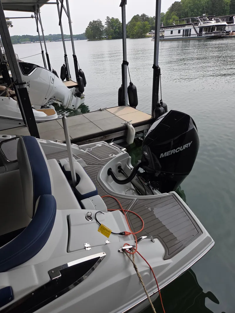 Slide: The Image of 2023 Crownline 260 XSS boat docked with Mercury outboard motor on a calm lake. - 13