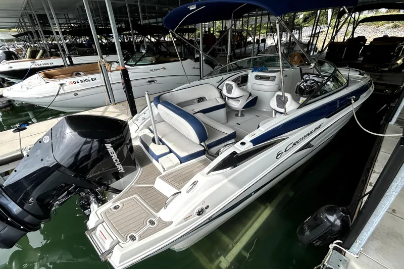 Slide: The Image of 2023 Crownline 260 XSS boat docked, featuring sleek design and Mercury outboard engine. - 14