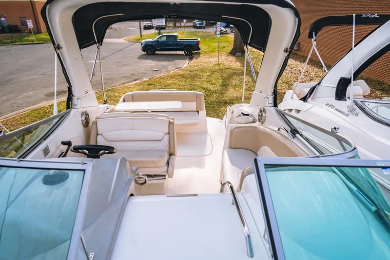 Slide: The Image of 2018 Chaparral 270 Signature boat interior with seating and helm, docked outdoors. - 1