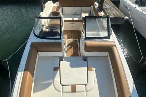 Slide: The Image of 2022 Bayliner DX2000 boat with tan and white seating, docked at a marina. - 3