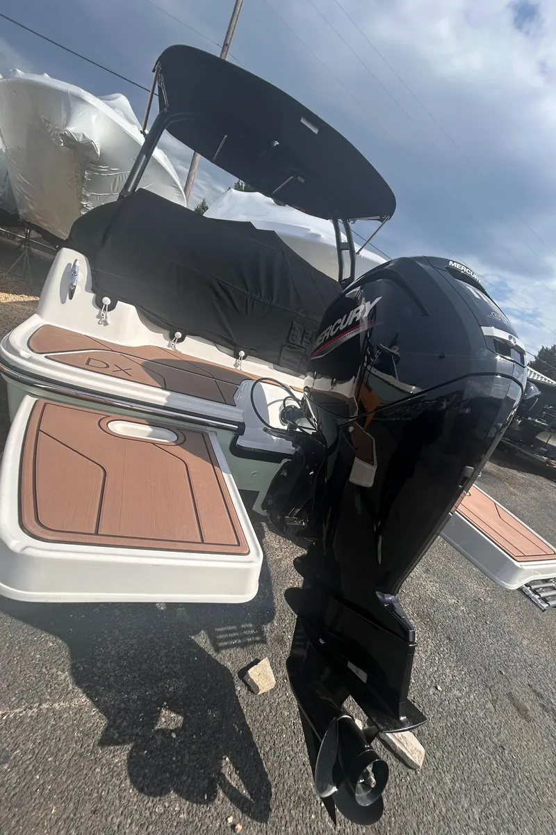 Slide: The Image of 2022 Bayliner DX2000 boat with outboard motor, docked under a cloudy sky. - 7