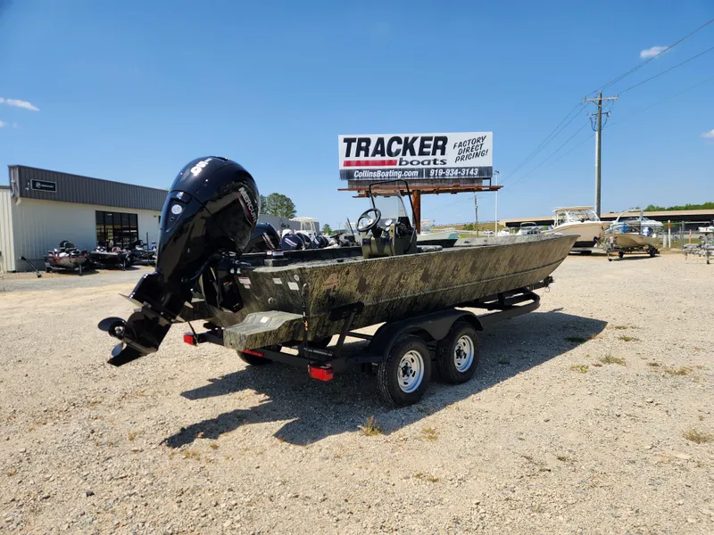 Slide: The Image of 2024 Tracker Grizzly 2072 CC boat on trailer in dealership lot under clear blue sky. - 2