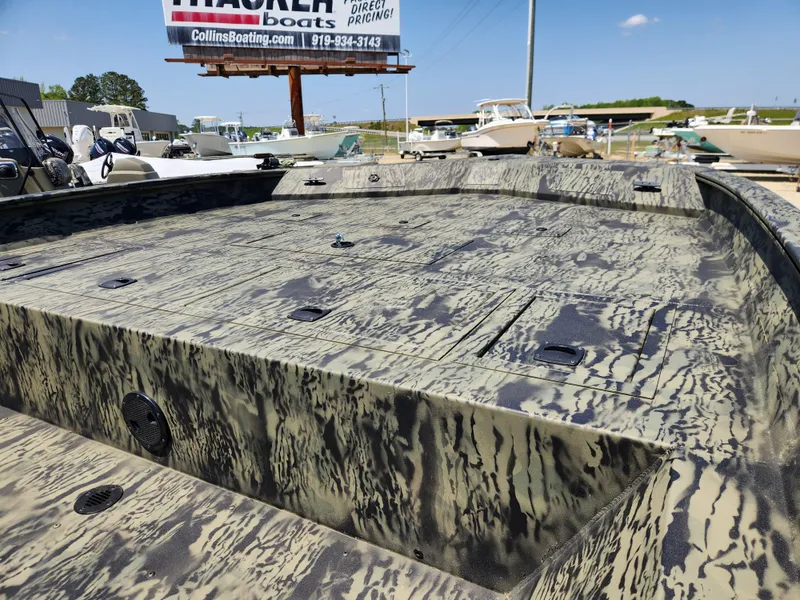 Slide: The Image of 2024 Tracker Grizzly 2072 CC boat with camouflage design in a marina setting. - 9