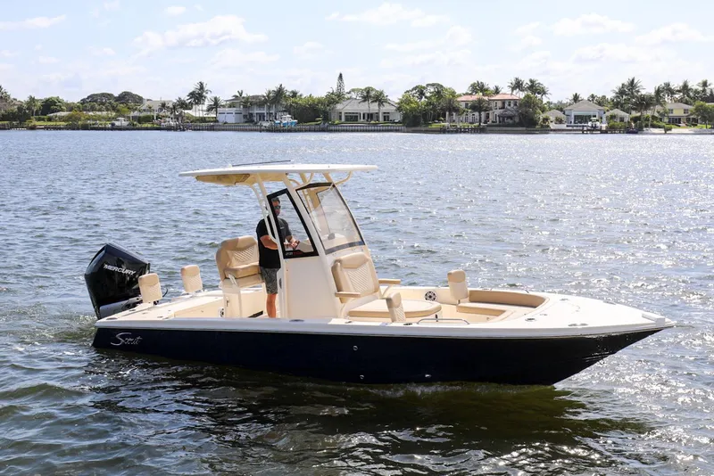 Slide: The Image of 2023 Scout 231 XSB boat cruising on a sunny day near waterfront homes. - 1