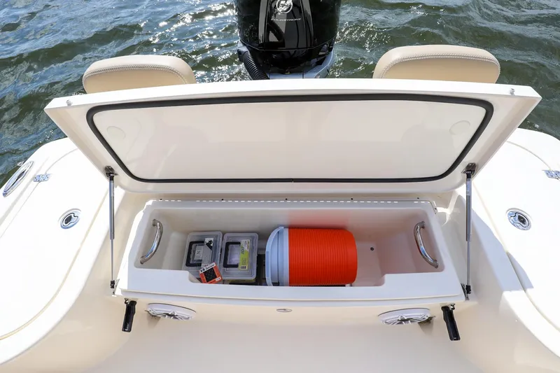 Slide: The Image of 2023 Scout 231 XSB boat storage compartment with cooler and gear on water. - 10