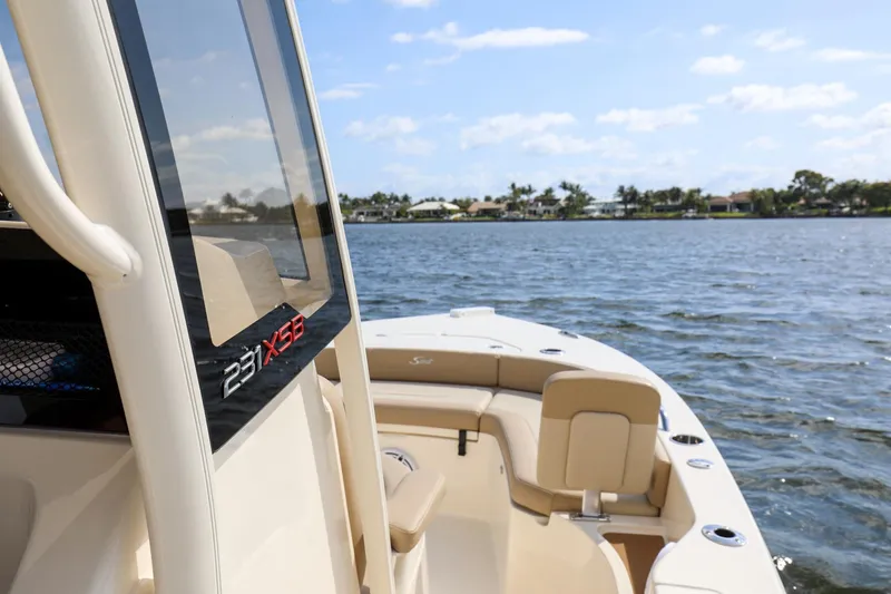 Slide: The Image of 2023 Scout 231 XSB boat on calm water, showcasing sleek design and spacious seating. - 11