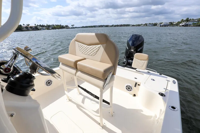 Slide: The Image of 2023 Scout 231 XSB boat interior with helm seat and outboard motor on a sunny day. - 12
