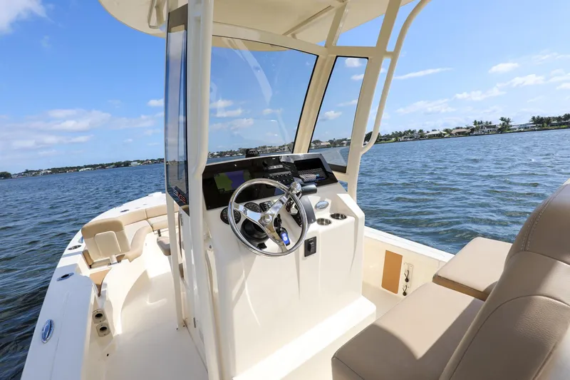 Slide: The Image of 2023 Scout 231 XSB boat interior with steering wheel, on a sunny day at sea. - 17