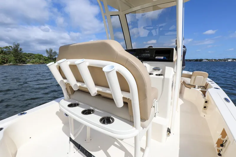 Slide: The Image of 2023 Scout 231 XSB boat interior with rod holders and seating on a sunny day. - 21