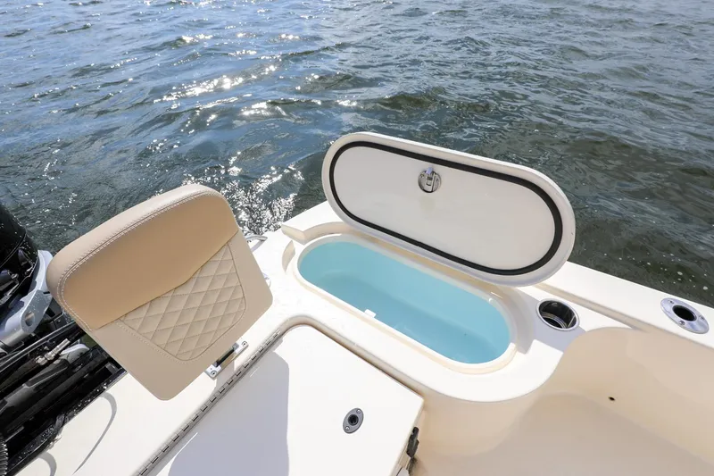 Slide: The Image of 2023 Scout 231 XSB boat with open storage compartment, beige seating, and water view. - 9