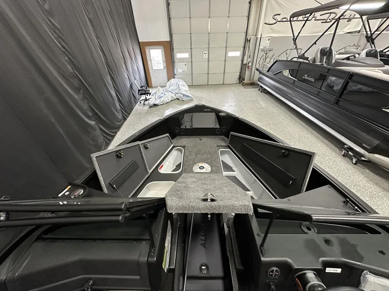 Slide: The Image of 2025 Alumacraft Competitor 175X Sport boat interior with open storage compartments in a showroom. - 7