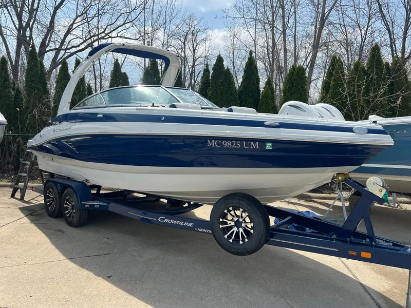 Slide: The Image of 2021 Crownline 255 SS boat on trailer, blue and white, parked outdoors. - 1