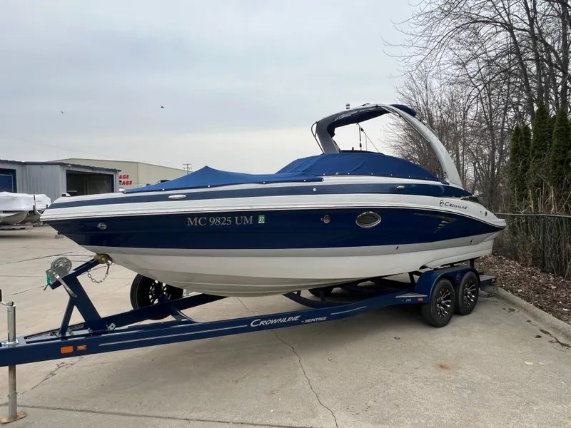 Slide: The Image of 2021 Crownline 255 SS boat on trailer, blue and white design, parked outdoors. - 2