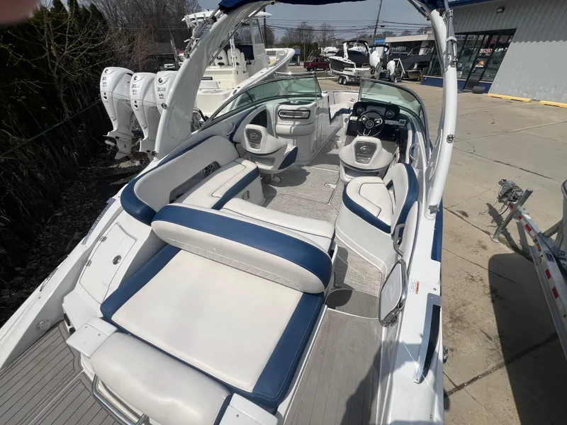 Slide: The Image of 2021 Crownline 255 SS boat interior with white and blue seating, docked outdoors. - 3